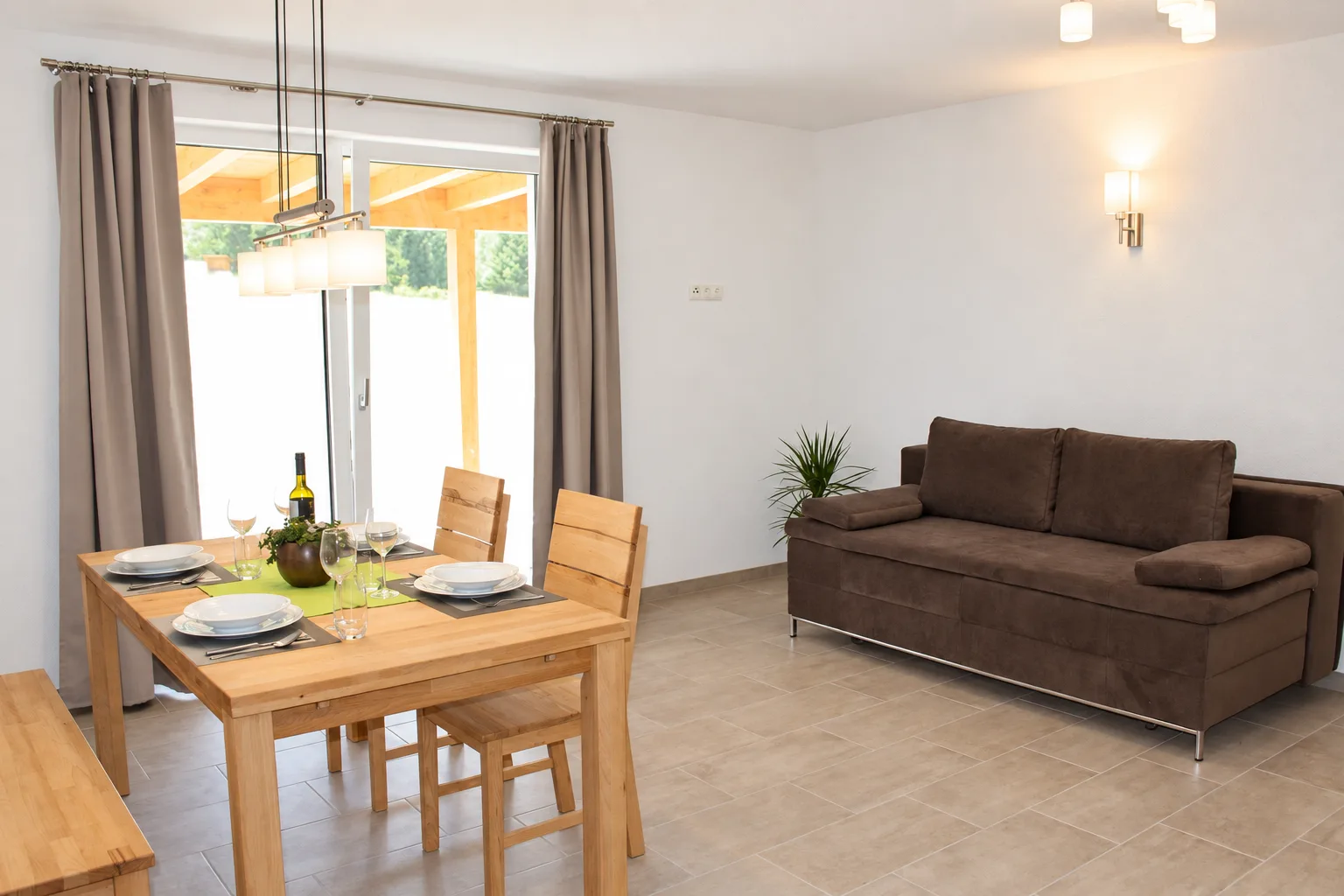 Wohn- und Essbereich mit gedecktem Holztisch und Sofa im Apartment Apart Alpenjuwel